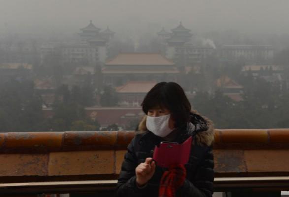 En turist fotograferar vid den historiska Jingshan-parken medan smogen sveper in Peking den 31 januari. En färsk rapport säger att Peking lider av överbefolkning. (Foto: Mark Ralston/AFP/Getty Images)