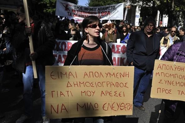 En grekisk journalist bär ett plakat under en 24-timmars strejk i Aten den 18 oktober. Grekiska journalister kommer att fortsätta strejken till den 6 november, som följd av att tre journalister stängdes av i tisdags. (Foto: Louisa Gouliamaki/AFP/Getty Images)