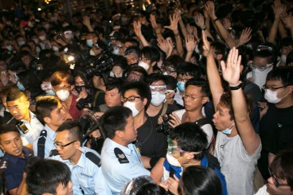 Prodemokratiska demonstranter håller upp sina händer för att visa poliserna att de är obeväpnade efter att de försökt stänga av Lung Wo Road för andra natten i rad i Hongkong den 16 oktober. (Benjamin Chasteen/Epoch Times)