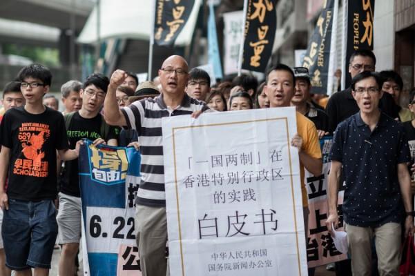 Demonstranter protesterar mot Pekings vitbok under en marsch på väg till ett kinesiskt representantkontor i Hongkong den 11 juni. I dagarna släppte Kina en vitbok som framhåller kontroll över Hongkong. (Philippe Lopez/AFP/Getty Images) 