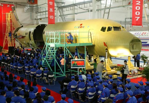 Tjänstemän och personal från Kinas största militära flygplanstillverkare vid en ceremoni för att fira prototypen av den första kommersiella jeten, ARJ-21, i Shanghai, den 30 mars 2007. (Foto: AFP/STR/China getting out) 
