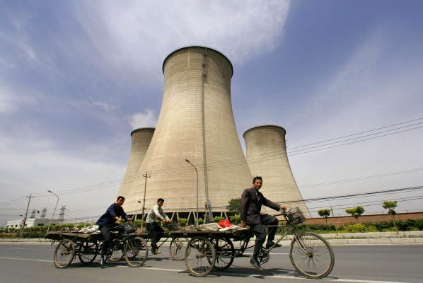 Migrantarbetare i Kina cyklar förbi kyltornen till ett kolkraftverk utanför Peking den 4 maj 2007. (Foto: AFP / Frederic J. Brown)