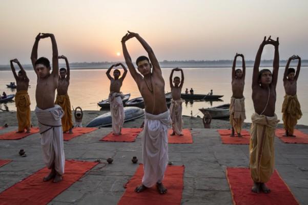 Unga indier tränar yoga vid floden Ganges i soluppgången. (Foto: Kevin Frayer/Getty Images)
