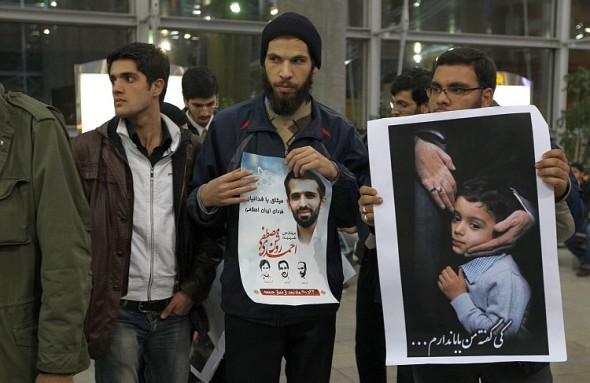 Iranska studenter håller upp ett foto av den mördade kärnfysikern Mostafa Ahmadi-Roshan och hans son i protest mot ankomsten av inspektörer från Internationella atomenergiorganet på Teherans flygplats den 29 januari. (Foto: Atta Kenare /AFP/Getty Images) 