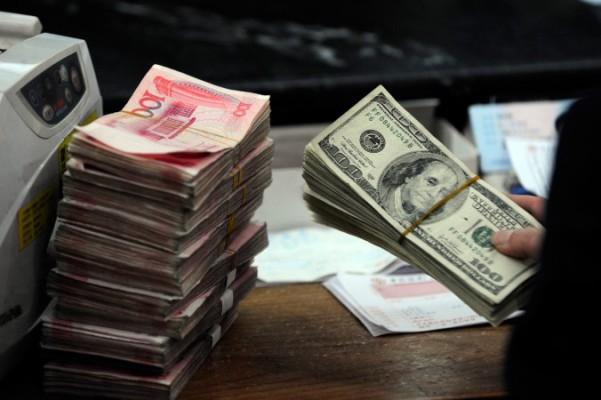 En kinesisk bankanställd i staden Hefei hanterar amerikanska dollar och kinesiska yuan, 9 mars 2010. Kinesiska myndigheter slår nu till mot illegala "pengabutiker" för att försöka hejda kapitalutflödet, men de stora problemen finns högre upp i systemet. Foto: STR/AFP/Getty Images
