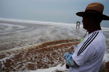 En kinesisk man ser på de höga vågorna vid kusten i Qingdao i Shandongprovinsen, Kina, den 8 augusti 2011. Tyfonen Muifa har rört sig norrut och dränkt stora delar av provinsen. (Foto: STR/AFP/Getty Images)