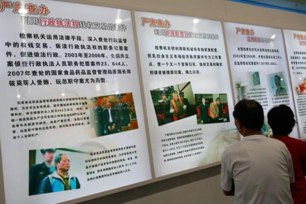Arkivfotot visar besökare som tittar på en anslagstavla om kinesiska partitjänstemän, anklagade för korruption, på en utställning i Peking den 2 september 2007. (Foto: Teh Eng Koon/AFP/Getty Images)