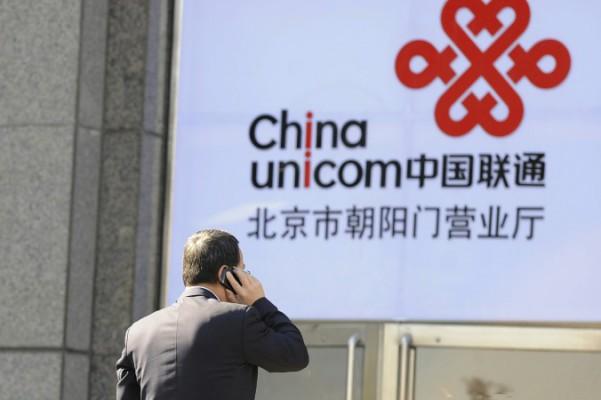 En kontorsarbetare pratar i en mobiltelefon framför China Unicoms logotype i Peking den 5 januari 2012. En antikorruptionsutredning har så här långt lett till gripandet av två höga chefer på China Unicom, som är en partner till Apple. (Foto: Liu Jin/AFP/Getty Images)
