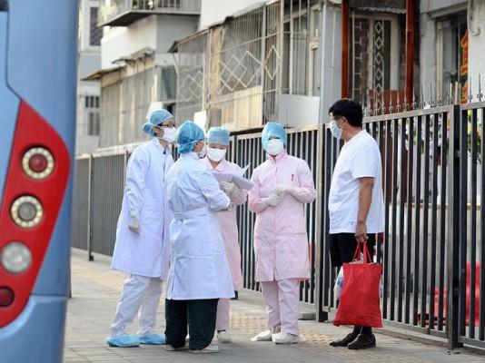Kinesisk medicinsk personal undersöker området runt ett vandrarhem i Peking där ett antal skolbarn satts i karantän efter att sju personer på deras skola diagnosticerats med svininfluensan, 2 juli 2009. (Foto: AFP/Getty Images)
