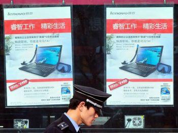 En säkerhetsvakt promenerar förbi reklamaffischer för datorer i Peking. (Frederic J. Brown/AFP/Getty Images)