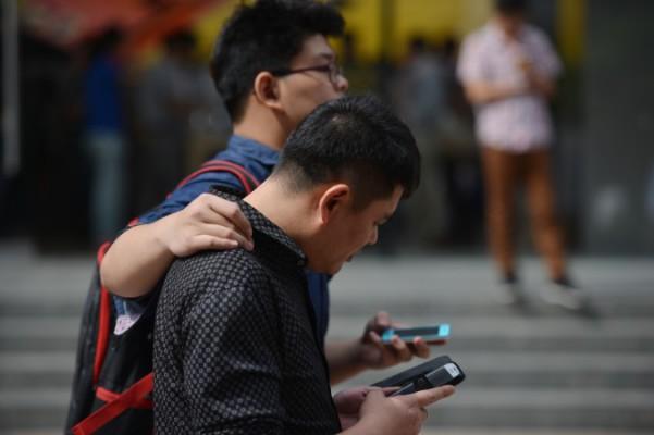 
Två män använder sina mobiltelefoner på en gata i Shanghai den 25 september 2013. (Foto: Peter Parks/AFP/Getty Images)                                             