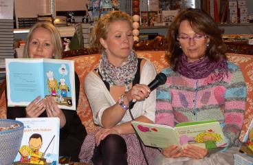 Linda Ulvaeus tillsammans med Johanna Lundqvist och Suzanne Reuter, som läser ur boken Leja Li och busbullen medan en stor skara barn sitter och lyssnar utanför butiken Underlandet i Kulturhuset i Stockholm. (Foto: Anne Hakosalo, Epoch Times)

