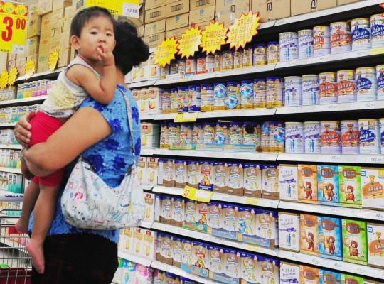 En kinesisk kvinna väljer mjölkprodukter för sitt barn på en stormarknad i Peking den 9 juli. (Foto: Franko Lee/AFP) 