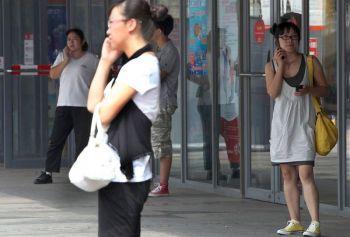 Kinesiska shoppare pratar i telefon utanför en galleria i Peking, 1 september förra året. Peking kommer etablera en "informationsplattform över Pekingbornas position", baserat på data från China Mobile Limiteds 17 miljoner mobiltelefoner i Peking. (Foto: Franko Lee/ AFP/Getty Images)