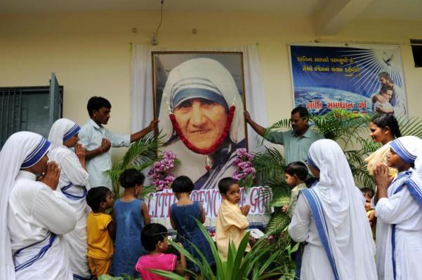 Indiska nunnor och föräldralösa barn ber framför ett porträtt av den avlidna Moder Teresa under firandet av hennes dödsdag för 12 år sedan, i Nirmala Sishu Bhavan i Ahmedabad. (Foto: Sam Panthaky/AFP/Getty Images)
