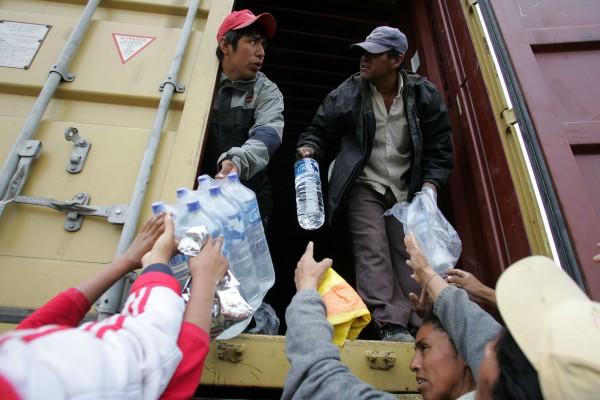 Vatten delas ut på motorvägen utanför Pisco den 19 augusti 2007. Hälsovårdsmyndigheterna i Peru kämpar nu med att förhindra smittsamma sjukdomar från att spridas efter jordbävningens ödeläggelse medan president Alan Garcia besökte området för att inspektera läget. (Foto: AFP/Eitan Abramovich) 
