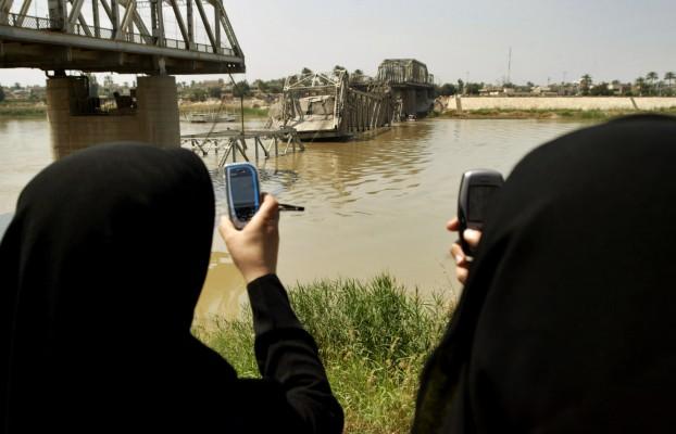 Irakiska kvinnor tar bilder av bron som kollapsade när självmordsbombare sprängde sig själva i en lastbil den 12 april 2007. Bomben dödade åtta personer då anfallet hände under morgonrusningen och folket åkte på bron över floden Tigris från shiaområdet till sunnidelen av staden Bagdad. (Foto: AFP/Ali Yussef)