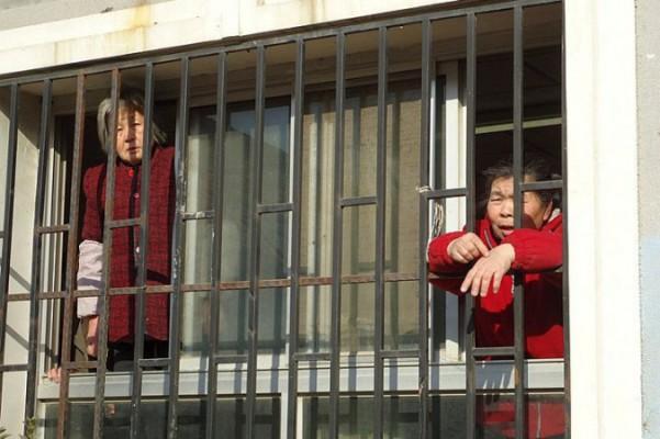 Petitionärer bröt sig ut ur ett utomrättsligt så kallat svart fängelse i Peking den 31 januari 2013. På detta arkivfoto lutar sig petitionärerna Chen Bixiang (t.v.) och Yu Hong ut ur fönstren till ett svart fängelse i Peking i januari 2012. (Foto tillhandahållet av en anonym källa i Kina).
