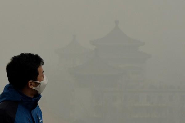 En turist med ansiktsmask tar sig uppför Jingshan-kullen utanför Den förbjudna staden samtidigt som svåra luftföroreningar fortsätter att svepa in Peking, den 26 februari 2014. (Foto: Mark Ralston/AFP/Getty Images)