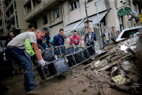 Folk bär sopor i centrala Genua den 11 oktober, efter att en person dog dagen innan när vattenmassorna svepte genom staden efter oväntat kraftigt nattligt regn som överraskade beslutsfattarna, trots liknande dödliga översvämningar för nästan tre år sedan. En av Genuas största floder, Bisagno, svämmade strax före midnatt över sina bräddar efter dagar av kraftigt regn. Floder av grumligt vatten forsade genom gatorna i den medeltida hamnstaden och krossade skyltfönster och svepte undan bilar. (Marco Bertorello /AFP Getty 