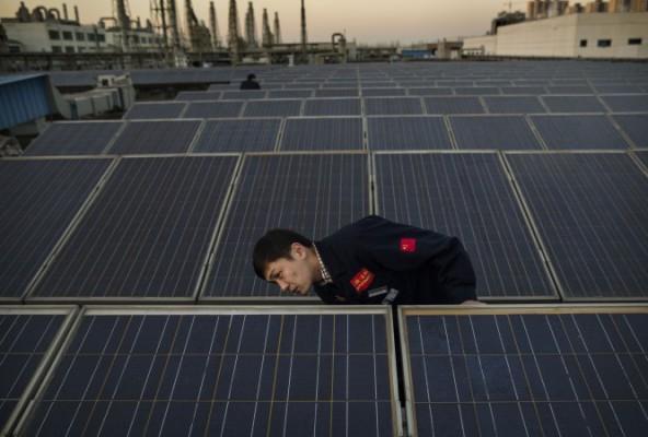 En chef på Yingli Solar kollar en solpanel på taket till företagets högkvarter i Baoding, Kina, 4 december 2014. (Kevin Frayer/Getty Images)
