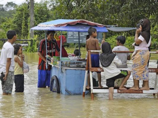 En man försöker sköta sitt matstånd omgiven av vattenmassor efter att nya översvämningar drabbat provinsen Narathiwat i södra Thailand den 2 januari 2012. (Foto: Madaree Tohlala/AFP/Getty Images)