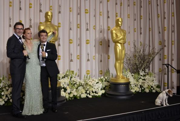 Regissören (v-h)Michel Hazanavicius, skådespelerskan Berenice Bejo och producent Thomas Langmann poserar med sina Oscars för filmen The Artist (The best picture) den 26 february 2012 i Hollywood, Kalifornien. Hunden Uggie sitter längre bort på scenen. (Foto: AFP/Joe Klamar). 