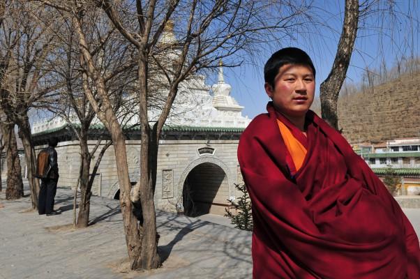 En tibetansk buddistmunk promenerar vid Kumbumklostret utanför Xining i mars 2009 i nordvästra Kina i Qinghaiprovinsen. I den stora tibetanska platån känd som Amdo. Kumbum är en av de sex stora klostren i den tibetanska buddismen och byggdes på helig mark 1577. (Foto: Frederic J. Brown/AFP) 