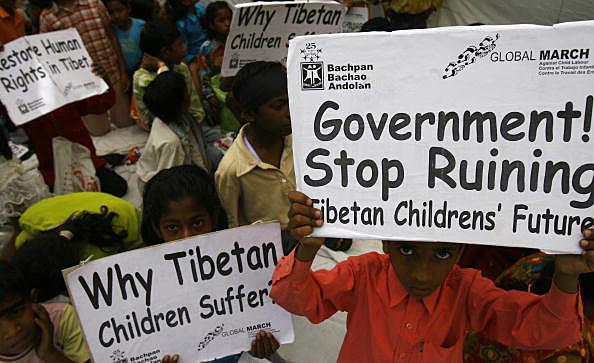 Tibetanska och indiska barn visar upp plakat vid minnesplatsen för Mahatma Gandhi i New Delhi. (Manpreet Romana/AFP/Getty Images)
