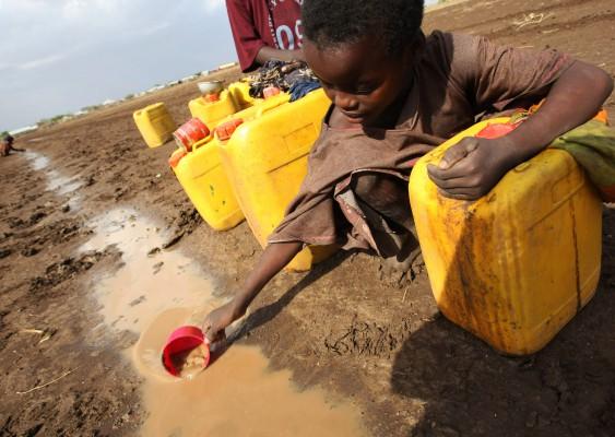 Ett barn öser upp vatten ur en pöl efter en regnstorm nära byn Torotoro, 125 km sydväst om Mogadishu, Somalien den 27 mars, 2009. Enligt lokal media dog minst 12 personer efter ett utbrott av akut diarré i byarna omkring regionen Jowhar. En lokal myndighetsperson sade att de flesta vattenställen i området hade torkat upp och folket var "desperata" efter vatten och tog till "desperata metoder". (Foto: Mohamed Dahir/ AFP)
