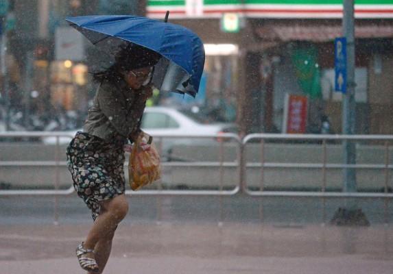 En kvinna söker skydd mot vinden under ett paraply i Taiwan när tyfonen Dujuan får landkänning. Foto: Sam Yeh/Getty Image