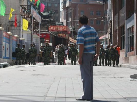 Attacken på Xinjiangs polisstation är den senaste våldsamma incidenten i detta oroliga område i nordvästra Kina. Här tittar en uigurisk man på medan kinesiska poliser blockerar en gata den 9 juli 2009 i Urumqi, huvudstad i den uiguriska autonoma regionen Xinjiang, Kina. (Foto: Guang Niu/Getty Images)