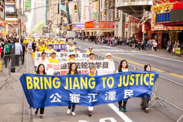 Falun Gong-utövare håller upp en banderoll om att dra kommunistpartiets förre ledare Jiang Zemin inför rätta för förföljelsen av Falun Gong. Bilden är tagen under en parad i New York, 15 maj 2015. (Foto: Edward Dye/Epoch Times