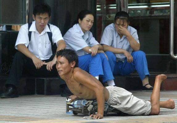 En handikappad tiggare på en gata i Peking, 2003. Tiggargäng i Kina sägs kidnappa och invalidisera barn för att använda dem som tiggare. (Foto: Frederic J. Brown/AFP/Getty Images)