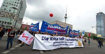 Demonstranterna marscherar bakom en banderoll med texten "Krisen beror på kapitalismen" under en demonstration i Berlin den 12 juni mot regeringens nedskärningsplaner. (Foto: Arno Burgi / AFP / Getty Images)