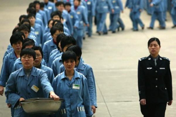 Fångar går bredvid en poliseskort under en öppen dag på ett fängelse i Nanjing, 2005. Västerländska företag har nyligen inlett utredningar angående påståenden om att hörlurar och annan elektronik som de köpt var tillverkade i ett kinesiskt tvångsarbetsläger. (Foto: STR/AFP/Getty Images)