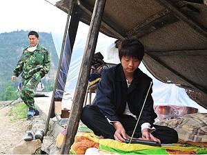 En överlevande lyssnar på radionyheterna i ett provisoriskt skydd nära den ödelagda staden Beichuan, som evakuerades av rädsla för efterskalv och jordglidningar, i jordbävningsdrabbade Sichuanprovinsen i sydvästra Kina. (Frederic J Brown/AFP/Getty Images)