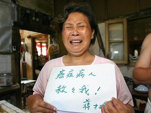 Jiang Caiyu, 48 år, gråter medan hon visar upp en skylt med texten ”Jag är cancerpatient, rädda mig” vid sitt hem i Shanghai, vilket ska rivas på order av affärsmannen Zhou Zhenyi. (Foto: Liu Jin/AFP/Getty Images)