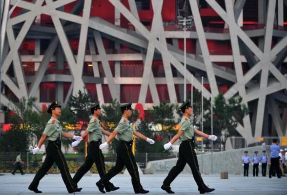 Informationskontroll är en viktig fråga för arrangörerna av Peking-OS. Här marscherar kinesiska soldater utanför olympiska huvudarenan, också känd som “fågelboet”. (Foto: FREDERIC J. BROWN/AFP/Getty Images)
