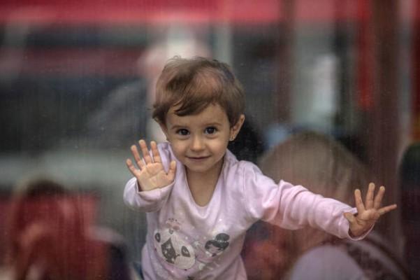 En flicka tittar ut från ett tåg, med vilket migranter reste från Ungern till Tyskland den 6 september 2015. Allt fler svenskar hör nu av sig och ställer upp som familjehem för ensamkommande flyktingbarn. Foto: Matt Cardy/ Getty Images