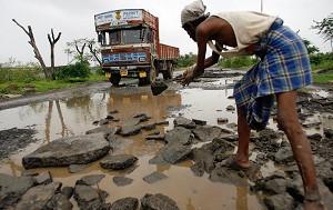 En indisk arbetare reparerar en förstörd väg i Mumbai. Experter menar att den dåliga infrastrukturen och de långsamma förbättringarna hindrar investeringstillfällen i Indien. (АщещЮ Pal Pillai/AFP/Getty Images)
