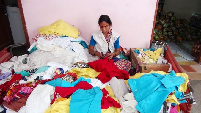 En anställd på Goonj sorterar kasserade kläder på organisationens kontor i New Delhi den 7 juni. Goonj samlar in, tvättar och lagar kasserade kläder som används som valuta till fattiga bybor, för att de ska hjälpa till med att bygga upp områdets infrastruktur, ett initiativ som kallas Kläder för arbete. (Foto: Venus Upadhayaya/Epoch Times)
