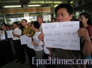 Arga demonstranter håller uppe handskrivna lappar med frågor om varför Shen Yun inställdes. (Hai Qing/The Epoch Times)
