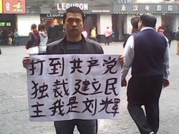 Liu Hui från Yan'an stod på den livliga Pekinggatan i Guangzhou den 13 och 14 februari med banderollerna ”Stoppa diktaturen” och ”Eliminera partiets förslavning av folket”. (Foto från en aktivistmedhjälpare)