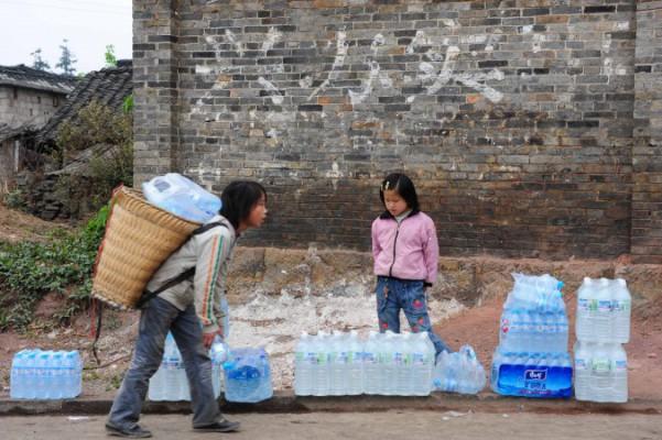 Kinesiska barn bär hem flaskor med dricksvatten i staden Qinglong i Yunnanprovinsen i sydöstra Kina. Foto: STR/AFP/Getty Images