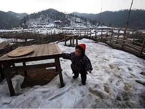 Efter den svåra vintern i Kina befaras jordskred längre fram i år. Detta barn leker i snön vid byn Dahuping i Yongxiulänet i Jiangxiprovinsen. (Foto: China Photos/Getty Images)