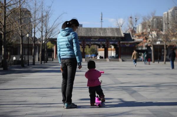 En kvinna och ett barn går i en park i Peking den 26 november 2013. De kinesiska familjeplaneringsmyndigheterna har nyligen nekat ersättning till föräldrar som förlorat sitt enda barn. (Foto: Wang Zhao/AFP/Getty Images)
