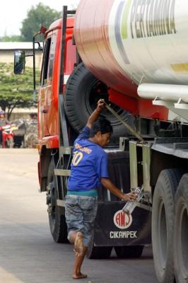En indonesisk pojke samlar bensin från en tankbil i Jakarta.  (Foto: AFP/Adek Berry)
