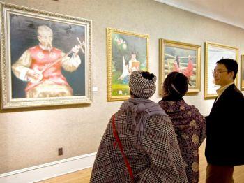En av NTDTV:s representanter diskuterar målningar med besökare på galleriet som ställer ut tavlor från NTDTV:s internationella, kinesiska tävling för figurativt måleri. Utställningen öppnades i söndags på Salmagundi Club, 5:e avenyn i New York. (Foto: Aloysio Santos/ Epoch Times)