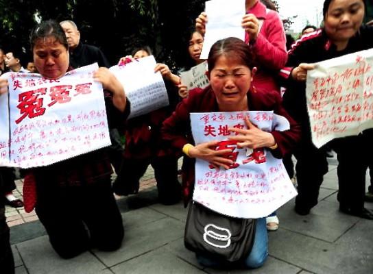 En grupp petitionärer knäböjer gråtande utanför en domstol i Chongqing i sydvästra Kina den 13 maj 2010, medan de håller upp plakat med fördömanden av statstjänstemän som tagit deras mark och egendom och olagligt hållit petitionärer fängslade i svarta fängelser. (Foto: AFP/AFP/Getty Images)